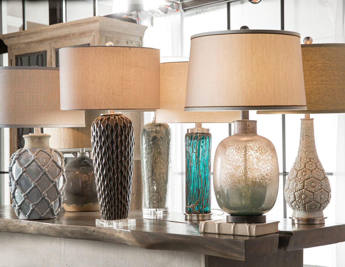 Various styles & sizes of designer tables lamps showcased on a console table.