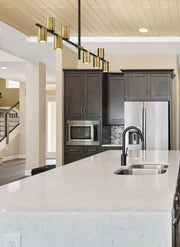 Calumet 8 Light 56" Linear Pendant in Matte Black + Olde Brass in a room setting